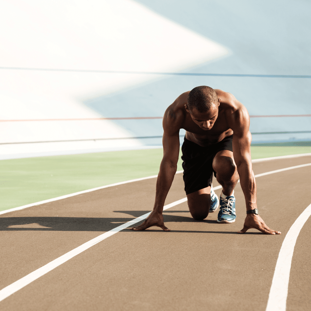 Läufer in Startposition auf der Bahn.