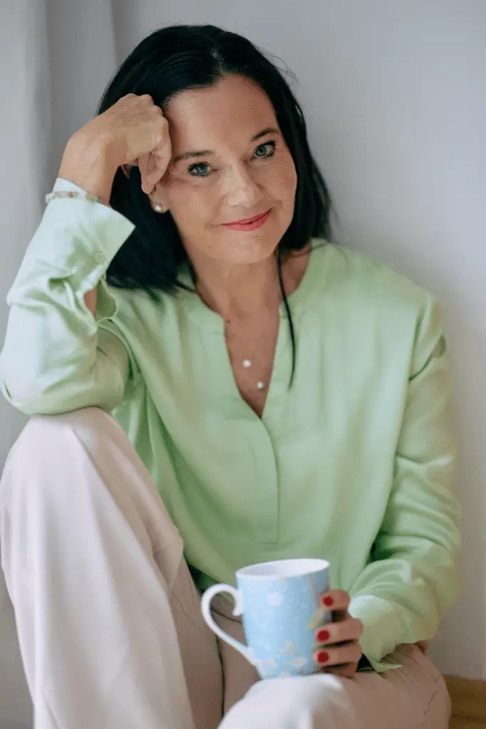 Frau hält Kaffeetasse und lächelt.